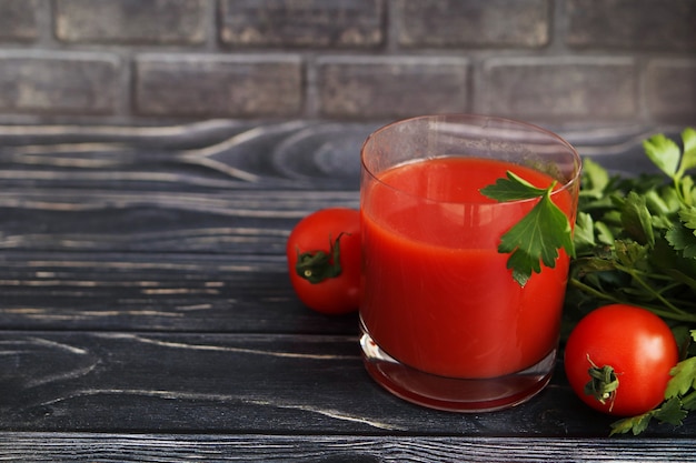 Jus de tomate dans un verre sur une surface en bois sombre