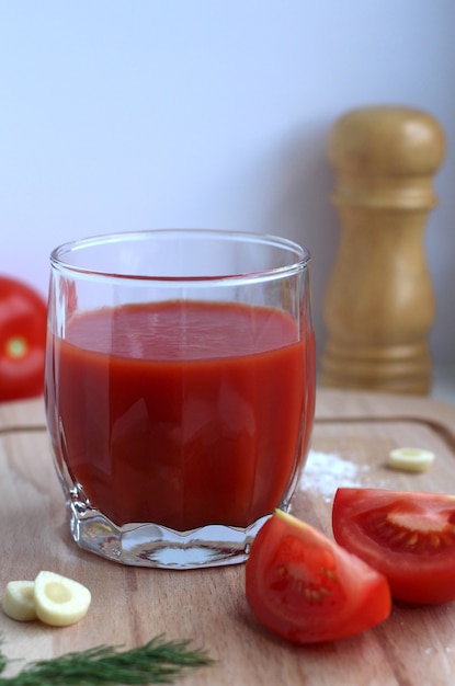 jus de tomate dans un verre en verre avec des tomates sel d'ail sur une planche en bois