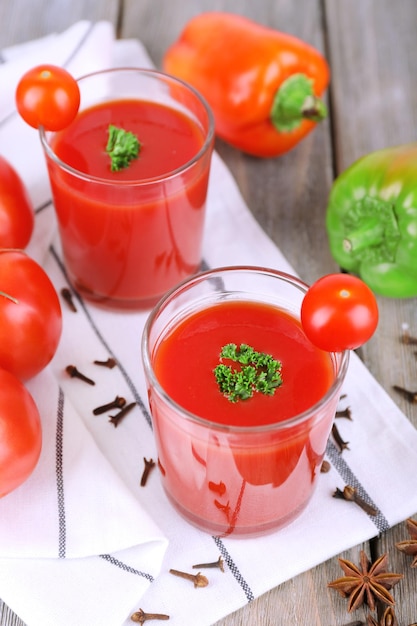 Jus de tomate dans des verres et des légumes frais sur une serviette sur fond de bois