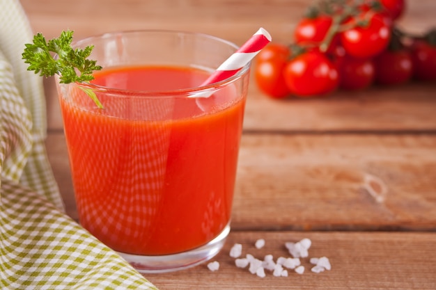 Jus de tomate avec du persil et du sel sur la table en bois