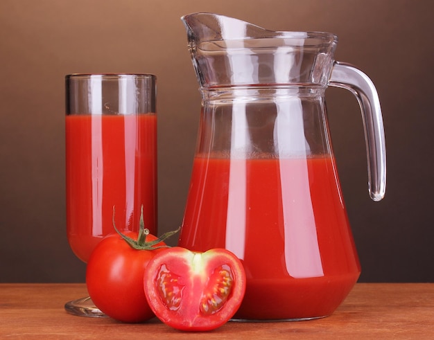 Jus de tomate en pichet et verre sur table en bois sur fond marron