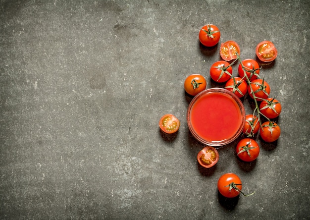 Jus de tomate et tomates entières. Table en pierre humide.