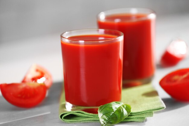 Jus de tomate et tomates fraîches sur une table en bois en gros plan