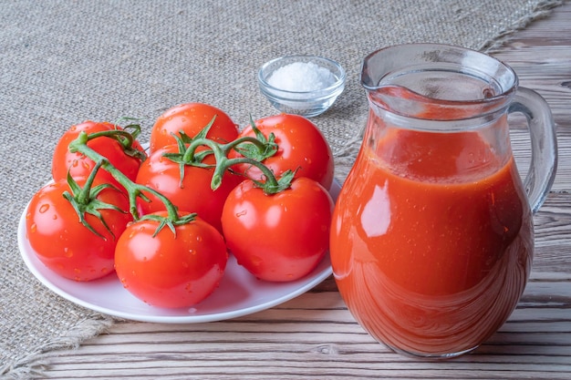 Jus de tomate de tomates fraîches avec une tasse de sel avec des tomates de jus sur le fond