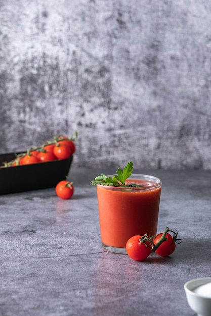 jus de tomate, verser du jus de tomate dans un verre, éclaboussures de jus de tomate, sur fond gris