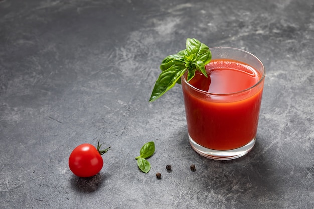 Jus de tomates fraîches biologiques dans un verre sur un fond sombre.