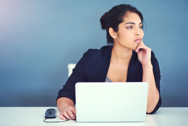 Juste un autre jour au bureau Photo recadrée d'une jeune femme d'affaires à l'air distraite à son bureau