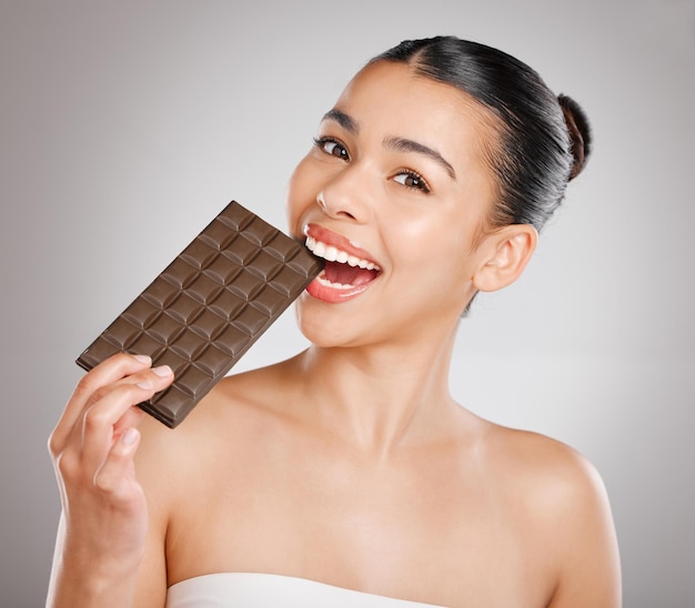 Juste une bouchée a dit que personne n'a jamais tourné en studio d'une jolie jeune femme mangeant une plaque de chocolat sur un fond gris