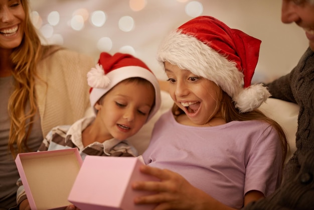 Juste ce que je voulais Une petite fille déballant un cadeau de Noël entourée de sa famille