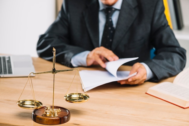 Justice à l'échelle de l'or devant un avocat tournant les pages d'un document dans la salle d'audience