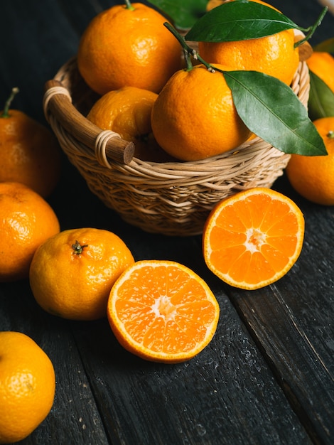 Juteux mandarines mûres vives dans un panier en bois sur fond sombre