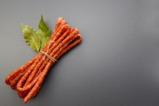 Photo kabanos polissent des saucisses séchées et des feuilles de laurier sur un fond gris