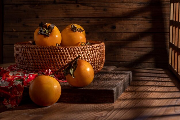 Les kakis sur l'assiette sont sur la table en bois dans une lumière sombre