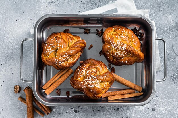 Kanelbullar - brioches suédoises à la cannelle dans un plat allant au four. Fond gris. Vue de dessus.