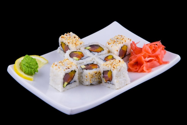 Kani avocat maki - Rouleaux avec chair de crabe, avocat et sésame sur une assiette blanche.