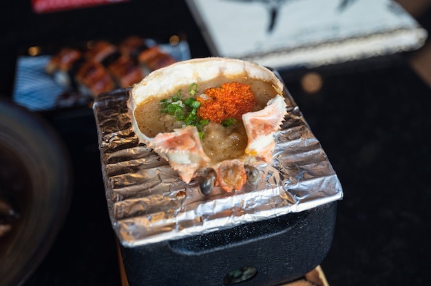 Kani Miso avec œufs de crevettes Ebiko dans une coquille de crabe grillé sur une cuisinière japonaise