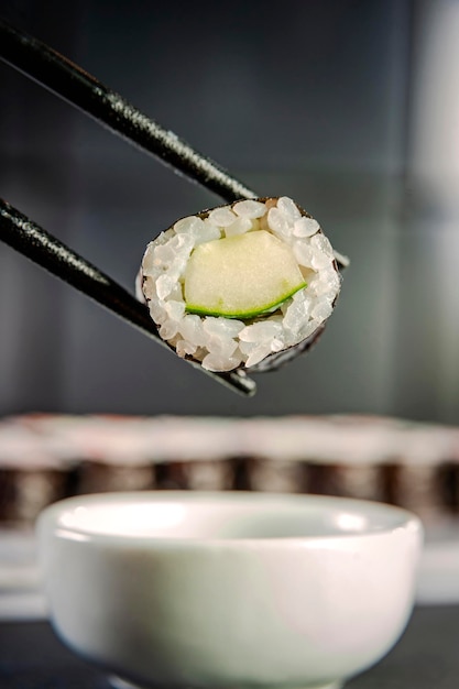 Photo kappamaki sur des baguettes avec des variétés de hossomaki sur un fond