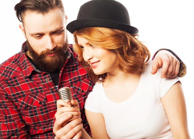 Karaoké - Beau couple avec microphone. Jeune et beauté. Style hipster. Sur fond blanc.