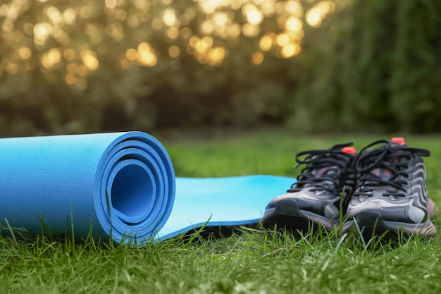 Karemat bleu ou tapis de fitness et baskets sur l'herbe verte à l'extérieur