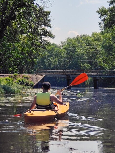 Kayak Un jeune homme descend la rivière en canoë Vue arrière Tourisme sportif et loisirs actifs