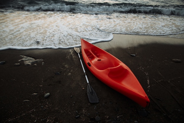 Kayak orange avec une rame au bord de la mer