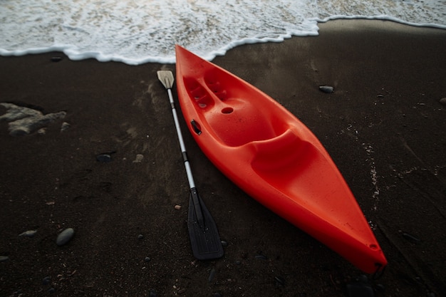 Kayak orange avec une rame au bord de la mer