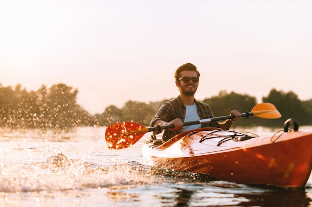 Kayak sur la rivière. Beau jeune homme souriant aux projections d'eau en kayak sur la rivière