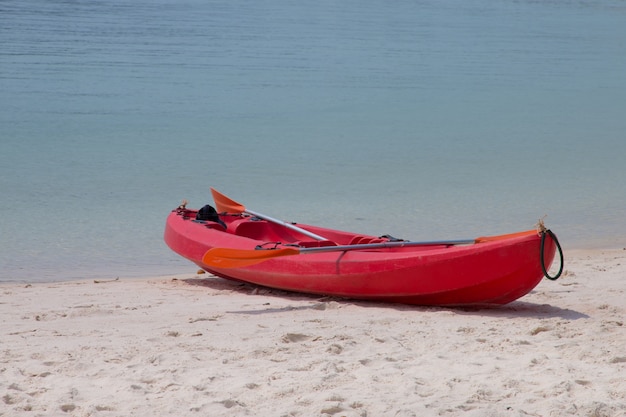 Un kayak rouge sur la plage avec une mer tropicale