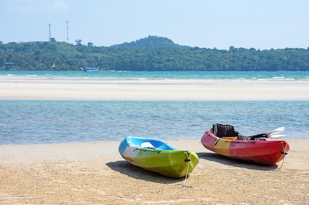 Kayak sur le sable de la mer, fond de montagnes et de rochers.