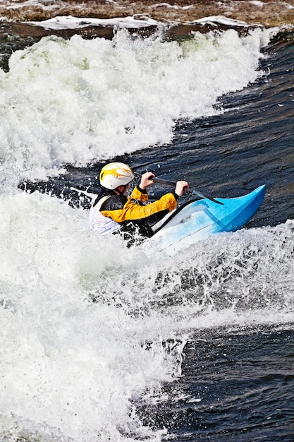 Un kayakiste masculin actif qui roule et surfe dans des eaux agitées