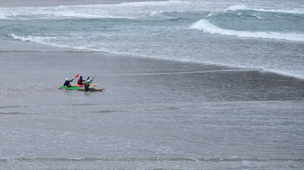 kayakistes entrant dans l'eau depuis le sable