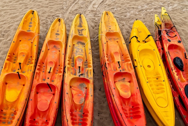 Kayaks en plastique aux couleurs vives jaune et rouge sur la côte de la plage de sable