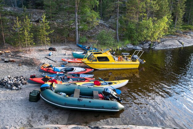 Kayaks touristiques et un bateau jaune dans une baie rocheuse et boisée du lac L'équipement est éparpillé autour des bateaux sur la rive