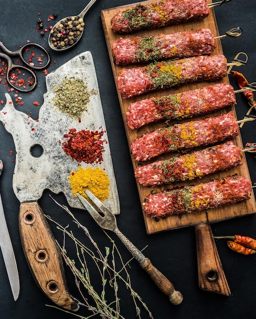 Kebab cru aux épices et vieille hache de cuisine sur un tableau noir