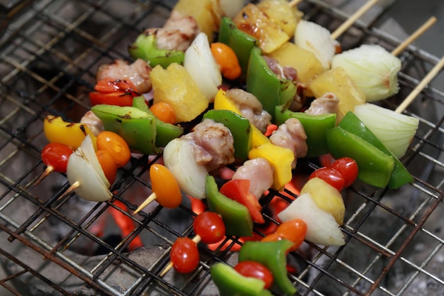 Kebab cru de viande sur un fond en bois avec des légumes.