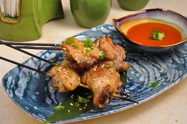 Kebab de cuisse de poulet asiatique savoureux sur un bâton de bambou avec sauce