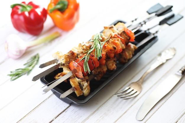 Photo kebab cuit sur des brochettes en métal avec des légumes servis sur une table blanche