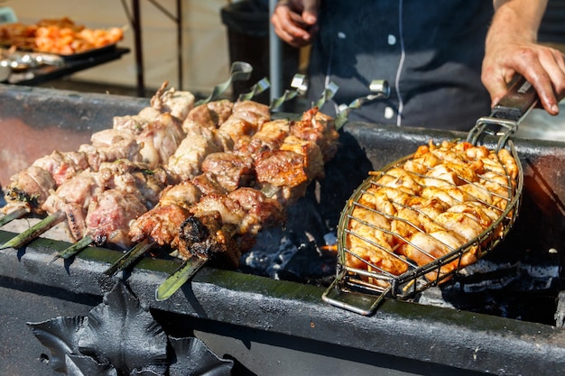 Kebab grillé cuisson sur brochette en métal. Viande rôtie cuite au barbecue. Plat oriental traditionnel, shish kebab. Grill sur charbon de bois et flamme, pique-nique, cuisine de rue