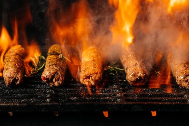 Kebab de viande d'agneau sur le gril avec des flammes de feu frotter l'agneau sur le gril du barbecue.