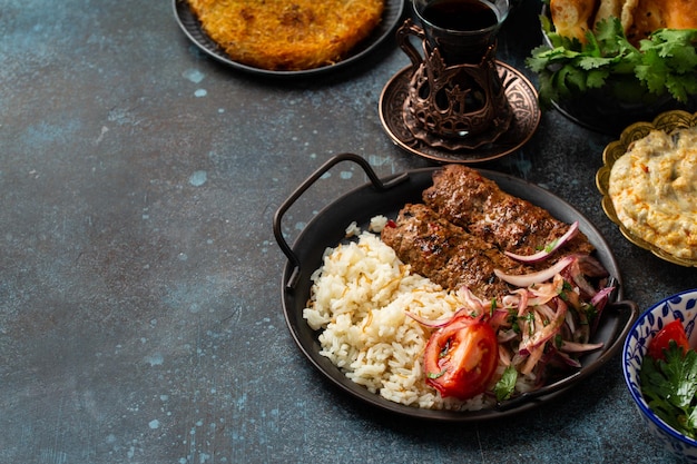 Kebab de viande de plat turc traditionnel avec des légumes de riz avec des apéritifs et du thé turc en verre Kebab sauce aubergine dessert au pain pita Kunefe et baklava espace de copie de repas du Moyen-Orient