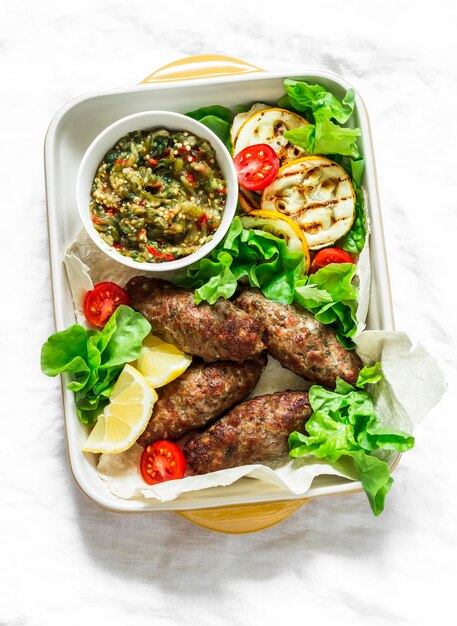 Kebab de viande rôtie légumes grillés sauce courgettes pain plat salade verte délicieux déjeuner de style méditerranéen sur fond clair vue de dessus