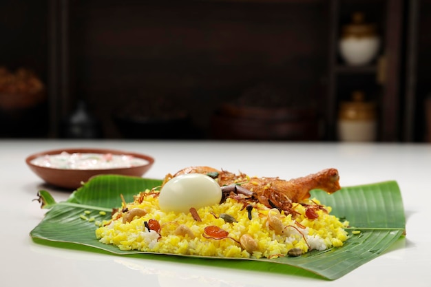 Kerala Chicken dum biryani disposés traditionnellement dans une feuille de bananier et raita