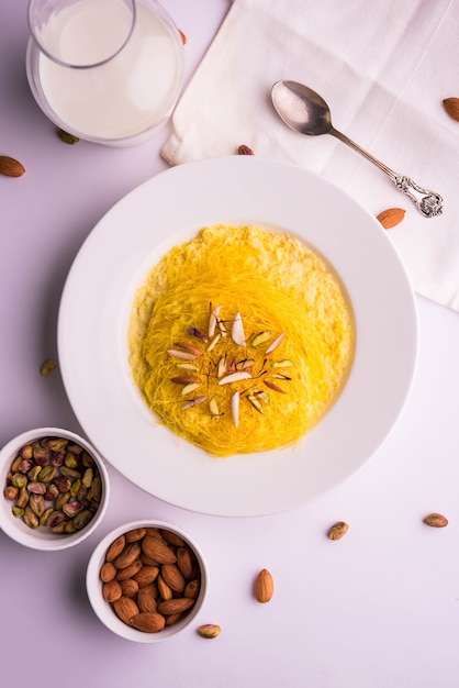 Kesar sutarfeni ou sutar feni ou firni ou seviyan ou laccha sucré indien, râpé, farine de riz floconneux rôti dans du ghee, mélangé avec du sucre fondu pour former une barbe à papa, avec de la pistache et des amandes