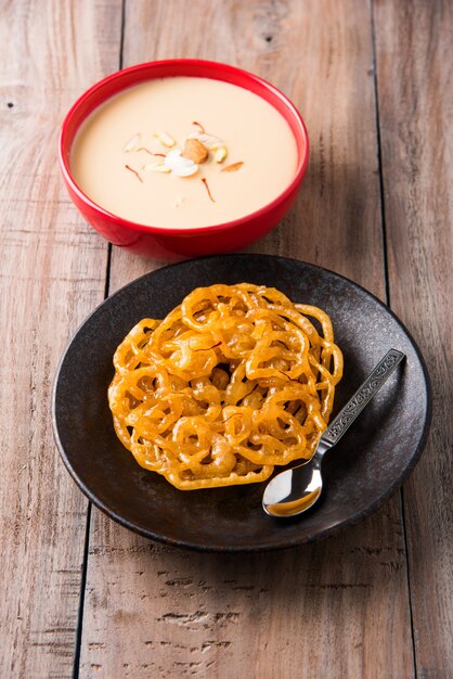 Kesari Jalebi ou Jilbi avec Rabdi est une délicieuse recette indienne servie comme dessert dans les festivals ou les mariages. Servi dans une assiette et un bol sur fond coloré ou en bois. Mise au point sélective