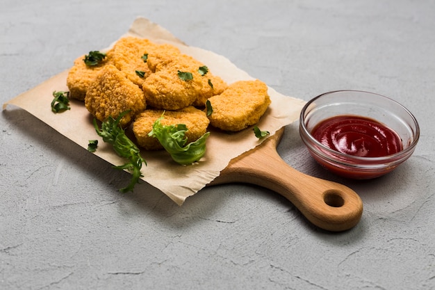 Ketchup près de la planche à découper avec des pépites