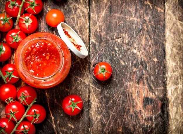 Ketchup de tomates, d'ail et d'épices dans un pot. Sur table en bois.