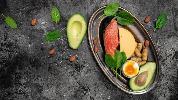 Keto régime alimentaire saumon avocat fromage oeuf épinards et noix Concept de régime cétogène à faible teneur en glucides Ingrédients pour la sélection d'aliments sains place pour la vue de dessus de texte