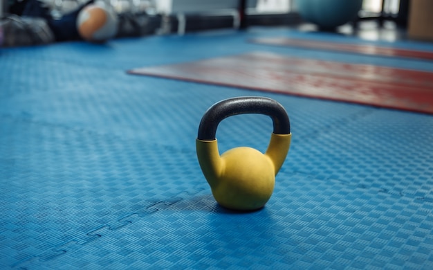 Kettlebell sur le sol avec revêtement en caoutchouc bleu dans la salle de sport