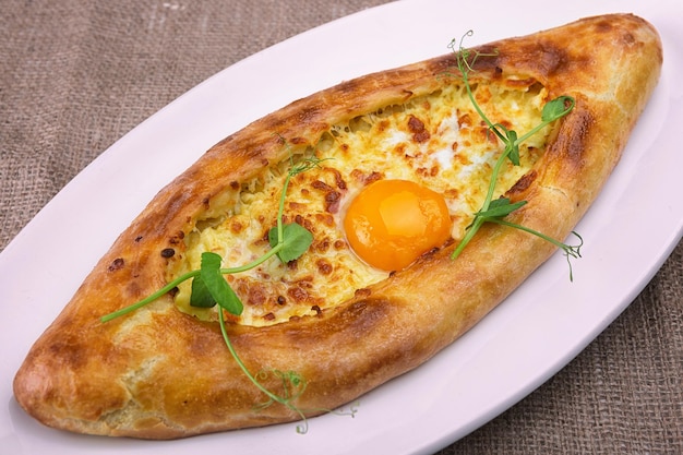 Khachapuri Adjarianstyle avec œuf et fromage sur une assiette blanche