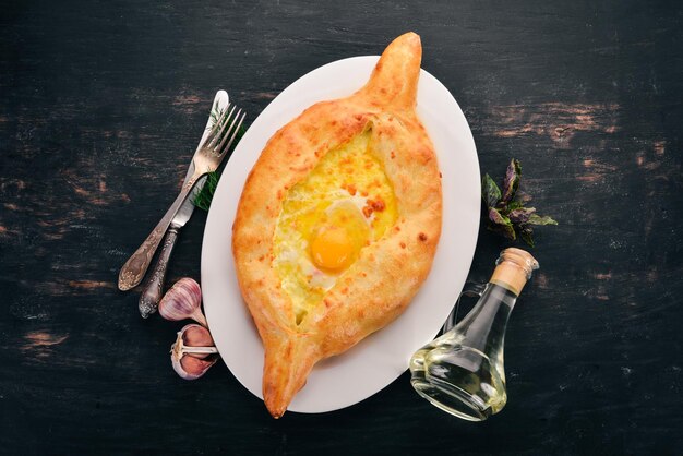 Khachapuri avec œuf et fromage Cuisine géorgienne Sur le vieux fond en bois Espace libre pour le texte Vue de dessus